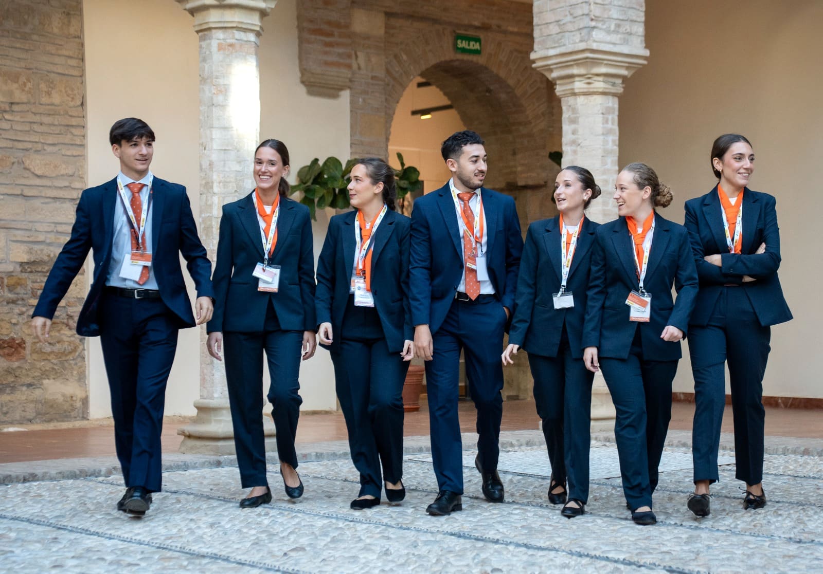 Siete integrantes del equipo de sala de Esmeeting caminan juntos por el patio de la sede de la Cumbre Internacional.