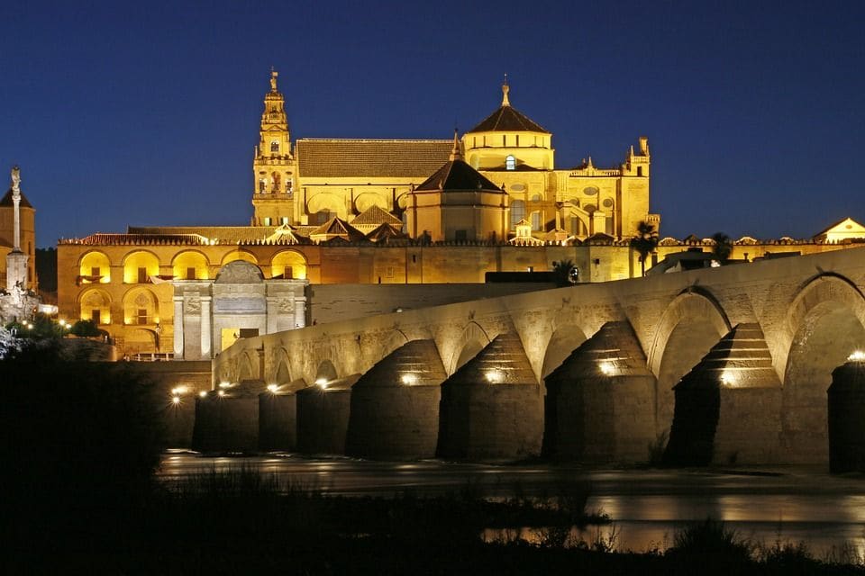El puente romano y la Mezquita-Catedral de Córdoba iluminados de noche.