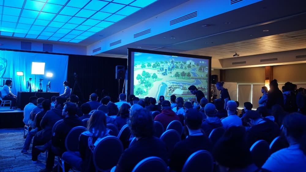Sala de un congreso llena de asistentes durante una ponencia, con la pantalla al fondo.