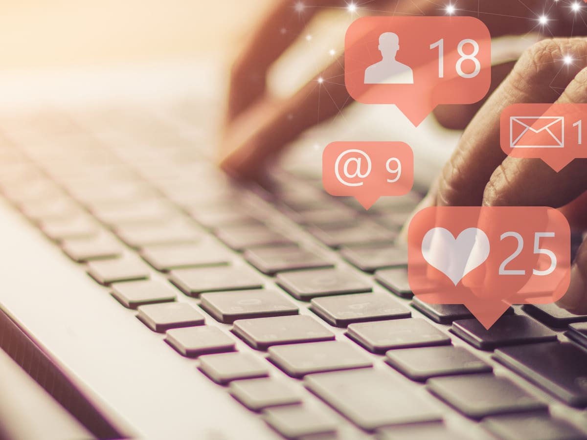Manos sobre un portátil con notificaciones de redes sociales.